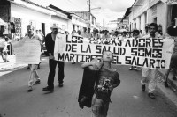 Image of sheet 19940710 photo 2: Ein junger Schuhputzer marschiert mit gestreckter Zunge vor einer Demo gegen die staatliche Lohnpolitik im Gesundheitswesen. Esteli, Nicaragua 1994 √

A shoecleaner marches in front of a demonstration against the cut of work and salaries in the medical health sector. protest