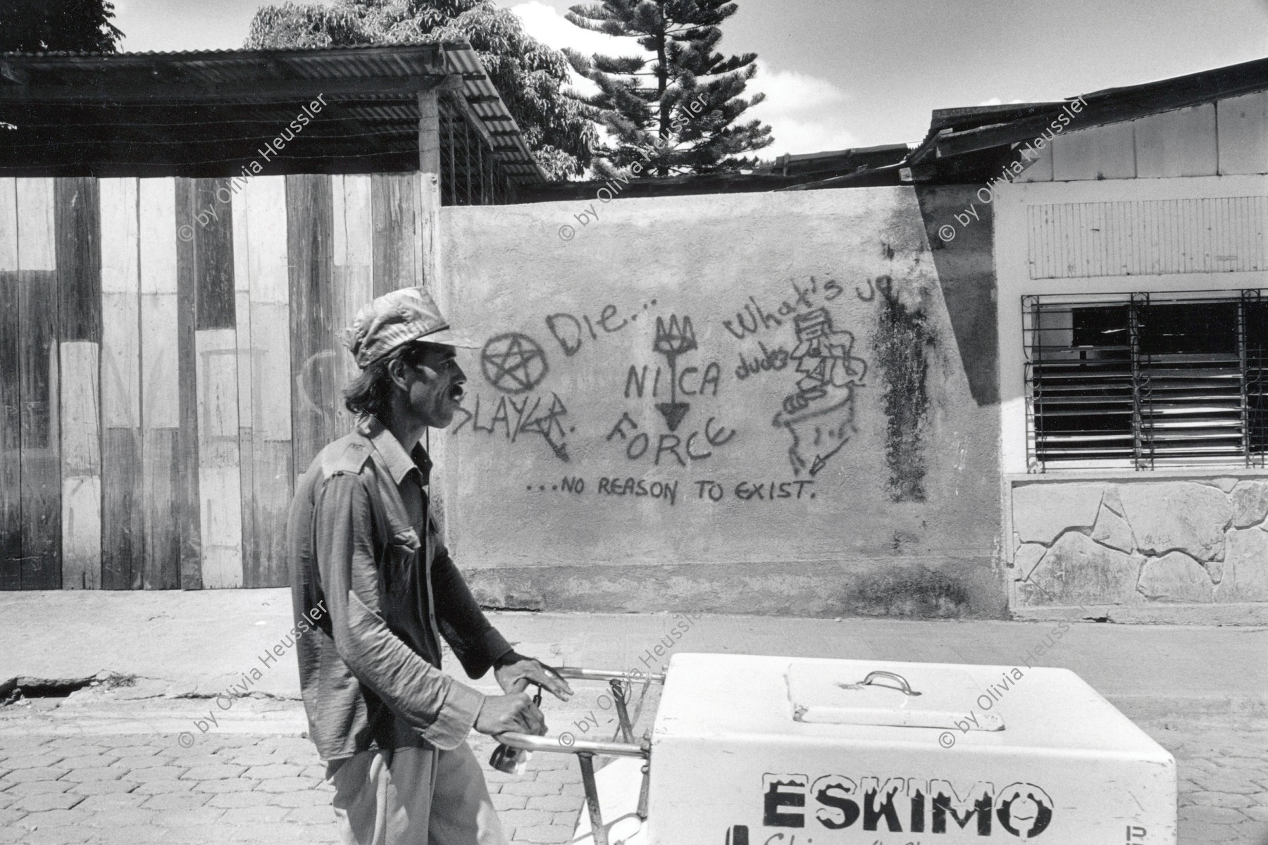 Image of sheet 19940720 photo 26: © 1994, Olivia Heussler / www.clic.li
Ein Eisverkäufer vor einem Graffiti in Esteli, Nicaragua 1994 √
Glacé Verkäufer fliegender Händler Ice Cream vendor Eskimo  Man street