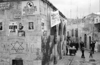 Image of sheet 19960060 photo 11: Strassenszene King Salomon Street Nr. 1-3 und Nr. 9- 24 mit Wahlpropadanda und NO + Davidstern graffitti. In der Altstadt Jerusalem Salbungsstein (hier wurde der Leichnam Christi gesalbt) in der Grabeskirche 3 griechisch-orthodoxe Altare im Kalvarienberg  rechts der Kreuzannagelungsaltar (von 1588) in der Mitte der (ebenfalls den Katholiken gehörende) Stabat-Mater-Altar links der Kreuzigungsaltar der Orthodoxen mit Loch in dem das Kreuz stand, und die Felsplatte,die sich nach der Kreuzigung öffnete. Auf dem Kalvarienberg werden Stationen X-XIII des Kreuzweges angenommen. Sicht auf die Altstadt vom Ölberg, Berg Ophel. Jüdischer Friedhof mit betenden Juden und Junge mit Esel. Israel 1996