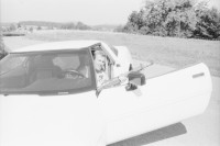 Image of sheet 19960730 photo 17: frtsg. Bettina Bräm auf Corvette mit Sturmgewehr vor Cannabisfeld. Arbeit macht frei. Vom Toitland Europa. Akko Theater Zentrum Israel am Zürcher Theaterspektakel. Mit Nr. 34 Haled Abu Ali. Zürich 1996