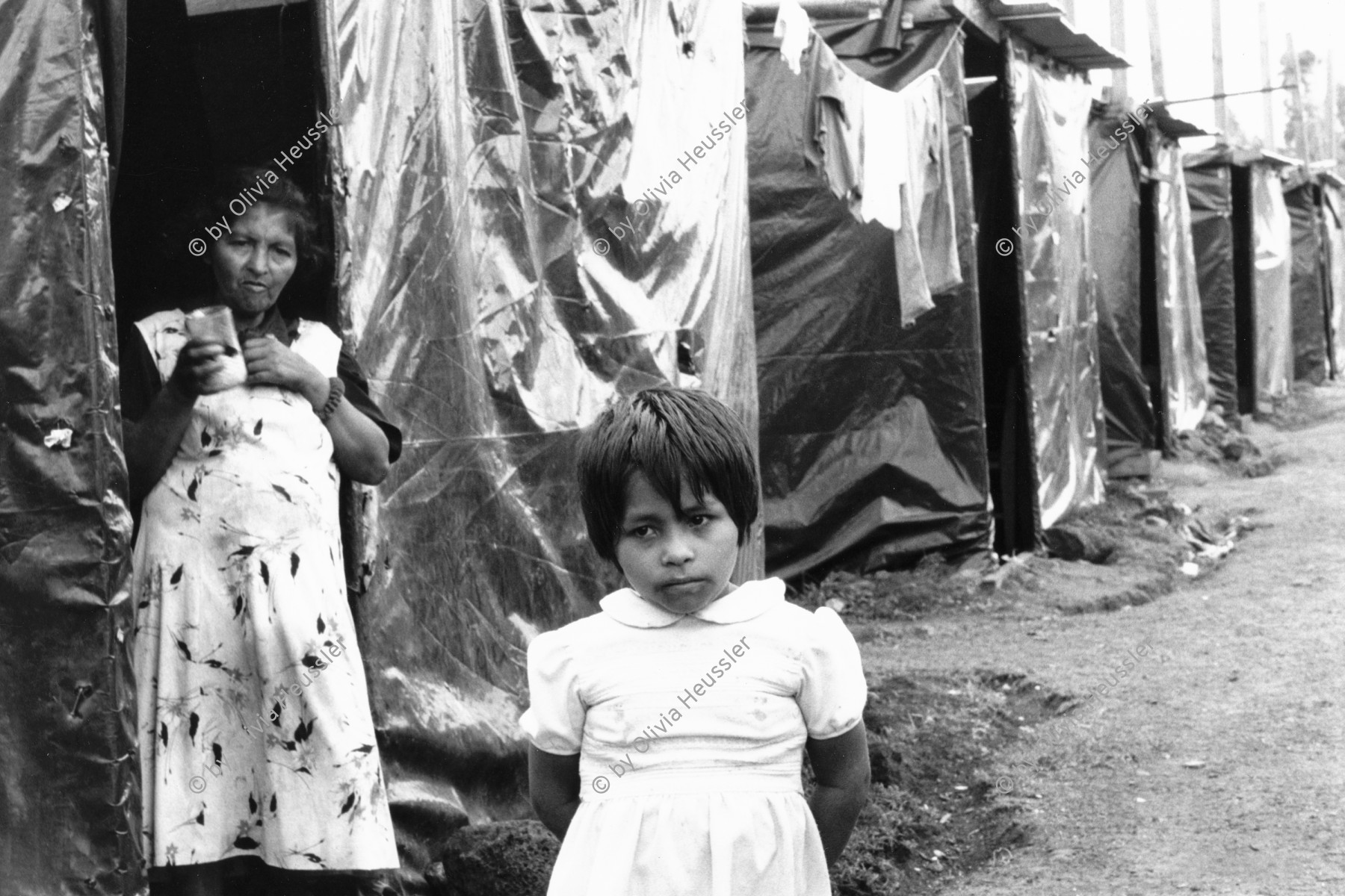 Image of sheet 19990040 photo 11: Opfer des Hurrikans Hurracan Mitch wohnen während der Regenzeit in Zelten mit schwarzen Plasitik plachen hütten. mother and child girl woman
Victims of Hurricane Mitch live in tents during the rainy season with black tarpaulins Plasitik huts.
Esteli Nicaragua Barrio Nuevo Amanecer, Mai 1999

√ © 1999, Olivia Heussler