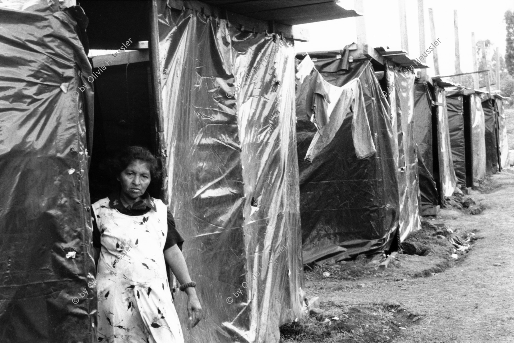 Image of sheet 19990040 photo 7: Opfer des Hurrikans Hurracan Mitch wohnen während der Regenzeit in Zelten mit schwarzen Plasitik plachen hütten.
Victims of Hurricane Mitch live in tents during the rainy season with black tarpaulins Plasitik huts. Woman 
Esteli Nicaragua America central Barrio Nuevo Amanecer, Mai 1999

√ © 1999, Olivia Heussler