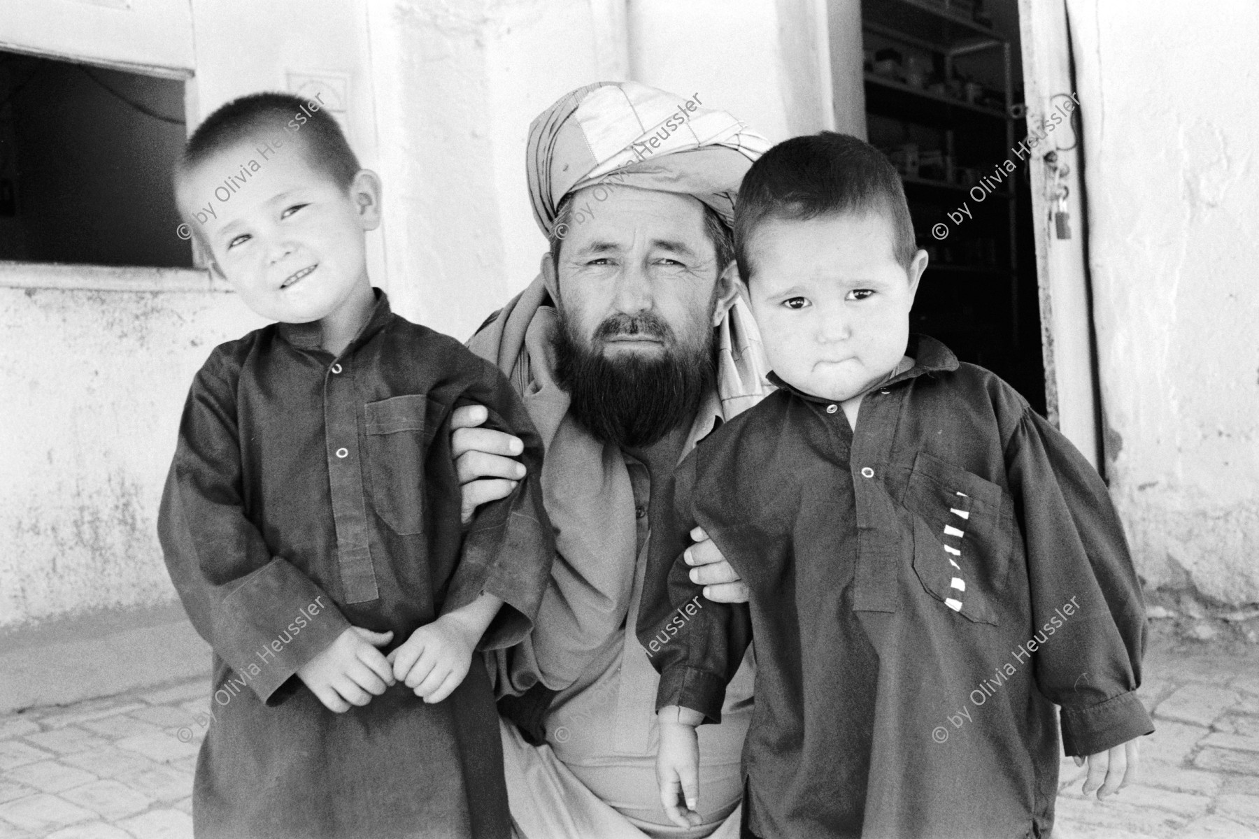 Image of sheet 20010070 photo 22: Mehr Abad, Pakistan Quetta Baluchistan 2001
Hazara Vater mit seinen Zwillingen. 
Hazara father with his twin boys.  √

Hazāra (Persian: هزاره‎) are a Persian-speaking people who mainly live in central Afghanistan. They are overwhelmingly Twelver Shia Muslims and comprise the third largest ethnic group of Afghanistan, forming about 9% (according to other sources up to 19%) of the total population. More than 650,000 Hazara live in neighbouring Pakistan (mostly settled in Quetta) and an estimated one million in Iran.

Balochistan (Balochi: بلوچستان) or Baluchistan (lit. Land of the Baloch) is an arid, desert and mountainous region on the Iranian plateau in south-western Asia, northwest of the Indian Ocean near the Persian Gulf. It mainly includes southwestern Pakistan, southeastern Iran and a smaller section of southwestern Afghanistan.

Belutschistan (persisch ‏بلوچستان‎) ist eine Region im Iranischen Hochland, die sich über den Osten Irans, den Süden Afghanistans und den Südwesten Pakistans erstreckt. Die Fläche beträgt etwa 300.000 km².

ONE TIME NON EXCLUSIVE EDITORIAL RIGHTS ONLY- NO ARCHIVING-NO THIRD PARTY DISTRIBUTION

© 2001, by OLIVIA HEUSSLER / www.clic.li