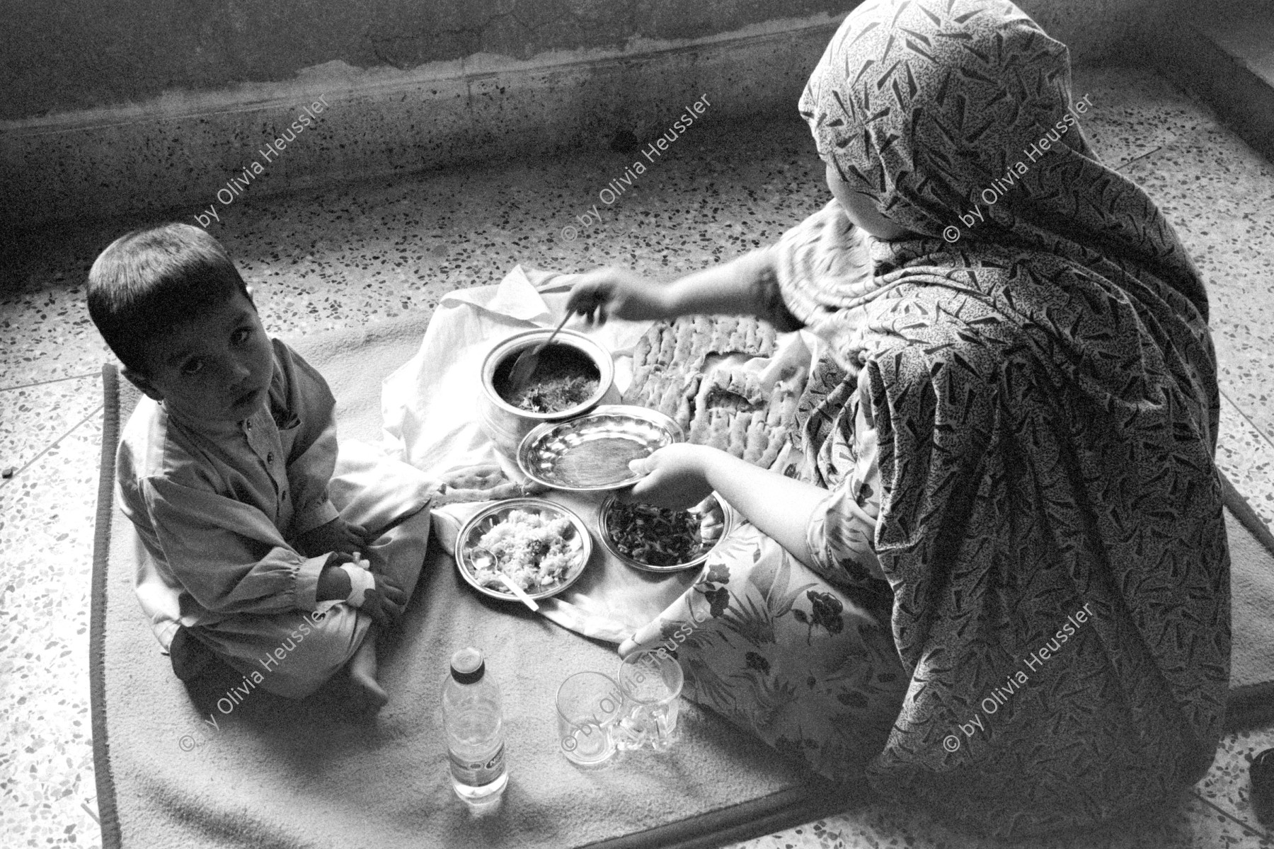 Image of sheet 20010070 photo 37: Mehr Abad, Pakistan Quetta Baluchistan 2001 √
Hazara Frau mit Kind Bube Junge
Hazara woman mother eating with her son
boy child food

Hazāra (Persian: هزاره‎) are a Persian-speaking people who mainly live in central Afghanistan. They are overwhelmingly Twelver Shia Muslims and comprise the third largest ethnic group of Afghanistan, forming about 9% (according to other sources up to 19%) of the total population. More than 650,000 Hazara live in neighbouring Pakistan (mostly settled in Quetta) and an estimated one million in Iran.

Balochistan (Balochi: بلوچستان) or Baluchistan[1] (lit. Land of the Baloch) is an arid, desert and mountainous region on the Iranian plateau in south-western Asia, northwest of the Indian Ocean near the Persian Gulf. It mainly includes southwestern Pakistan, southeastern Iran and a smaller section of southwestern Afghanistan.

Belutschistan (persisch ‏بلوچستان‎) ist eine Region im Iranischen Hochland, die sich über den Osten Irans, den Süden Afghanistans und den Südwesten Pakistans erstreckt. Die Fläche beträgt etwa 300.000 km².

ONE TIME NON EXCLUSIVE EDITORIAL RIGHTS ONLY- NO ARCHIVING-NO THIRD PARTY DISTRIBUTION

© 2001, by OLIVIA HEUSSLER / www.clic.li