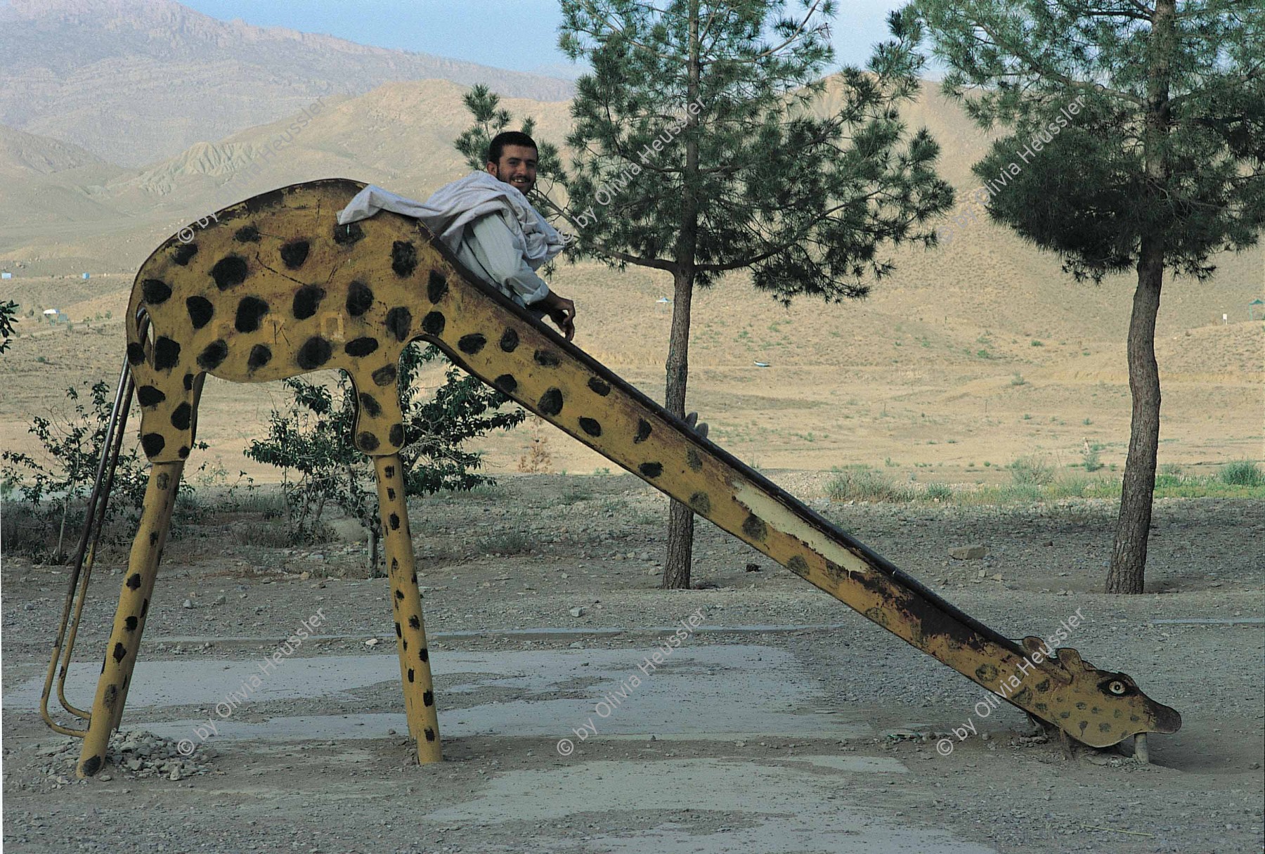 Image of sheet 20013001 photo 5: Ein Mann auf Rutschbahn in Form eines Giraffen,
Pakistan Quetta Baluchistan 2001. 
Lake Hanna.