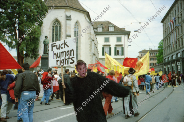 Image of sheet 20020190 photo 1: 1. Mai Demo Demonstration  gegen Busch George Bush Masken Affen Köche Koch Kochen ehemaliger Tessiner Nationalrat der Sozialdemokraten Franco Cavalli an der Demo am Limmatquai füttert Frau Tauben. 
Gotthard Wilhem Tell Abbildung auf Smart Auto Autobahn Galerien im Regen