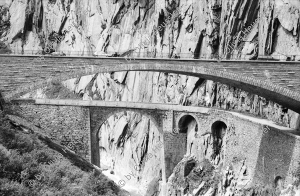 Image of sheet 20020400 photo 2: Gotthardstrasse Schöllenen Strassenbrücke von 1956 überspannt jene von 1830 die Säumerbrücke von 1200 befand sich ganz unten in der Schlucht. Viadukt Schöllenenbahn Teufelsbrücke Suwarow-Denkmal Memorial  
Urnerloch erstes Tunnel der Schweiz.
Kletterer am Klettersteig
Schülergruppe Touristen Andermatt Militärkaserne militärisches Uebungsgebiet Mic Ganz Michael
Urserental Felder Rentner Alois Regli mit Frau und Freunden vor dem 'Sybfiggler' auf Bank in Andermatt Eingang Bunker im Feld am Berg Kanton Uri, Schweiz Switzerland
Heute baut dort der ägyptische Bauunternehmer Samih Sawiri ein Ferien-resort.
aus: Gotthard, das Hindernis verbindet.