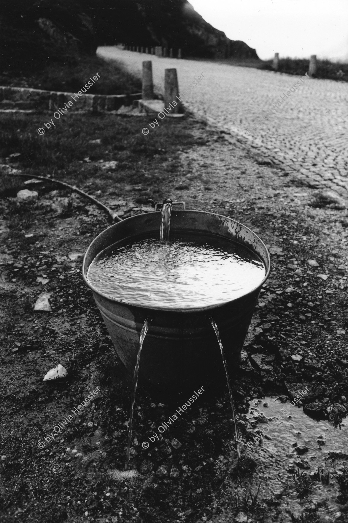 Image of sheet 20020560 photo 10: Tremola am Gotthardpass alte Gotthardstrasse 
Zinnbecken Wanne mit Wasser gefuellt zwei Löcher Kuhtränke 
Schweiz, Svizzera, Switzerland Water Kanton Tessin Ticino 2002 √ Aus: Gotthard, das Hindernis verbindet.
copyright by Olivia Heussler
Exhibition »Via Gotthard«, Leica Camera Galerie Bienne 2003