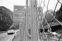 Image of sheet 20020680 photo 13: Autoschlangen auf der Nordachse des Gotthardpasses Teufelsstein am Nordportal Gotthard Strassentunnel Uri Wohnwagen Belüftungsanlage vor Operalpbahn Alis steht vor Flieger Denkmal und Passhöhentafel Gotthard Hospiz Cervelat Bratwurst Stand Urserental oberhalb Andermatt