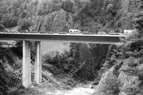 Image of sheet 20020680 photo 8: Autoschlangen auf der Nordachse des Gotthardpasses Teufelsstein am Nordportal Gotthard Strassentunnel Uri Wohnwagen Belüftungsanlage vor Operalpbahn Alis steht vor Flieger Denkmal und Passhöhentafel Gotthard Hospiz Cervelat Bratwurst Stand Urserental oberhalb Andermatt