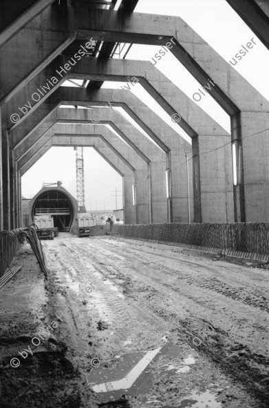 Image of sheet 20020790 photo 13: Neat Bahntunnel Gotthardbasistunnel Baustelle Suedportal
AlpTransit Gotthard AG  Südportal in Bodio 
Durchstich zur Oströhre Faido Gruppenbild Mineure zur Feier des ersten Durchbruchs im Basistunnel. 
...Wir sind zur Feier in den Gotthard-Basistunnel gekommen: den ersten Durchbruch im Jahrhundertbauwerk, nämlich von der Lockergesteinszone in die nördlich anschliessende Oströhre. Vor der Tunnelbrust steht erhöht wie auf einer Bühne ein gelber, von Scheinwerfern angestrahlter Bagger. Ende der Lockergesteinszone, die Tunnelbrust, auf der das auszubrechende Profil mit roten Punkten markiert ist, besteht aus solidem , monolithischem Leventinagranit. Die Mineure strömen in den Stollen, Lautsprecher werden montiert. ... Durch die Oeffnung sehen wir in die Oströhre hinüber...
Arbeiter der Firma Herrenknecht an der TBM
aus: Gotthard, das Hindernis verbindet. Kanton Tessin, Ticino, Schweiz Svizzera, Switzerland 2002