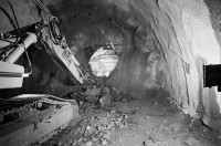 Image of sheet 20020790 photo 26: Neat Bahntunnel Gotthardbasistunnel Baustelle Suedportal
AlpTransit Gotthard AG  Südportal in Bodio 
Durchstich zur Oströhre Faido  Feier des ersten Durchbruchs im Basistunnel. 
"...Wir sind zur Feier in den Gotthard-Basistunnel gekommen: den ersten Durchbruch im Jahrhundertbauwerk, nämlich von der Lockergesteinszone in die nördlich anschliessende Oströhre. Vor der Tunnelbrust steht erhöht wie auf einer Bühne ein gelber, von Scheinwerfern angestrahlter Bagger. Ende der Lockergesteinszone, die Tunnelbrust, auf der das auszubrechende Profil mit roten Punkten markiert ist, besteht aus solidem , monolithischem Leventinagranit. Die Mineure strömen in den Stollen, Lautsprecher werden montiert. ... Durch die Oeffnung sehen wir in die Oströhre hinüber..."

aus: Gotthard, das Hindernis verbindet. 
Kanton Tessin, Ticino, Schweiz Svizzera, Switzerland 2002 √