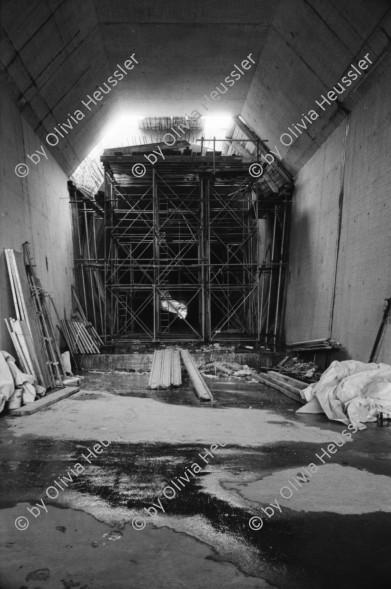 Image of sheet 20020790 photo 6: Neat Bahntunnel Gotthardbasistunnel Baustelle Suedportal
AlpTransit Gotthard AG  Südportal in Bodio 
Durchstich zur Oströhre Faido Gruppenbild Mineure zur Feier des ersten Durchbruchs im Basistunnel. 
...Wir sind zur Feier in den Gotthard-Basistunnel gekommen: den ersten Durchbruch im Jahrhundertbauwerk, nämlich von der Lockergesteinszone in die nördlich anschliessende Oströhre. Vor der Tunnelbrust steht erhöht wie auf einer Bühne ein gelber, von Scheinwerfern angestrahlter Bagger. Ende der Lockergesteinszone, die Tunnelbrust, auf der das auszubrechende Profil mit roten Punkten markiert ist, besteht aus solidem , monolithischem Leventinagranit. Die Mineure strömen in den Stollen, Lautsprecher werden montiert. ... Durch die Oeffnung sehen wir in die Oströhre hinüber...
Arbeiter der Firma Herrenknecht an der TBM
aus: Gotthard, das Hindernis verbindet. Kanton Tessin, Ticino, Schweiz Svizzera, Switzerland 2002