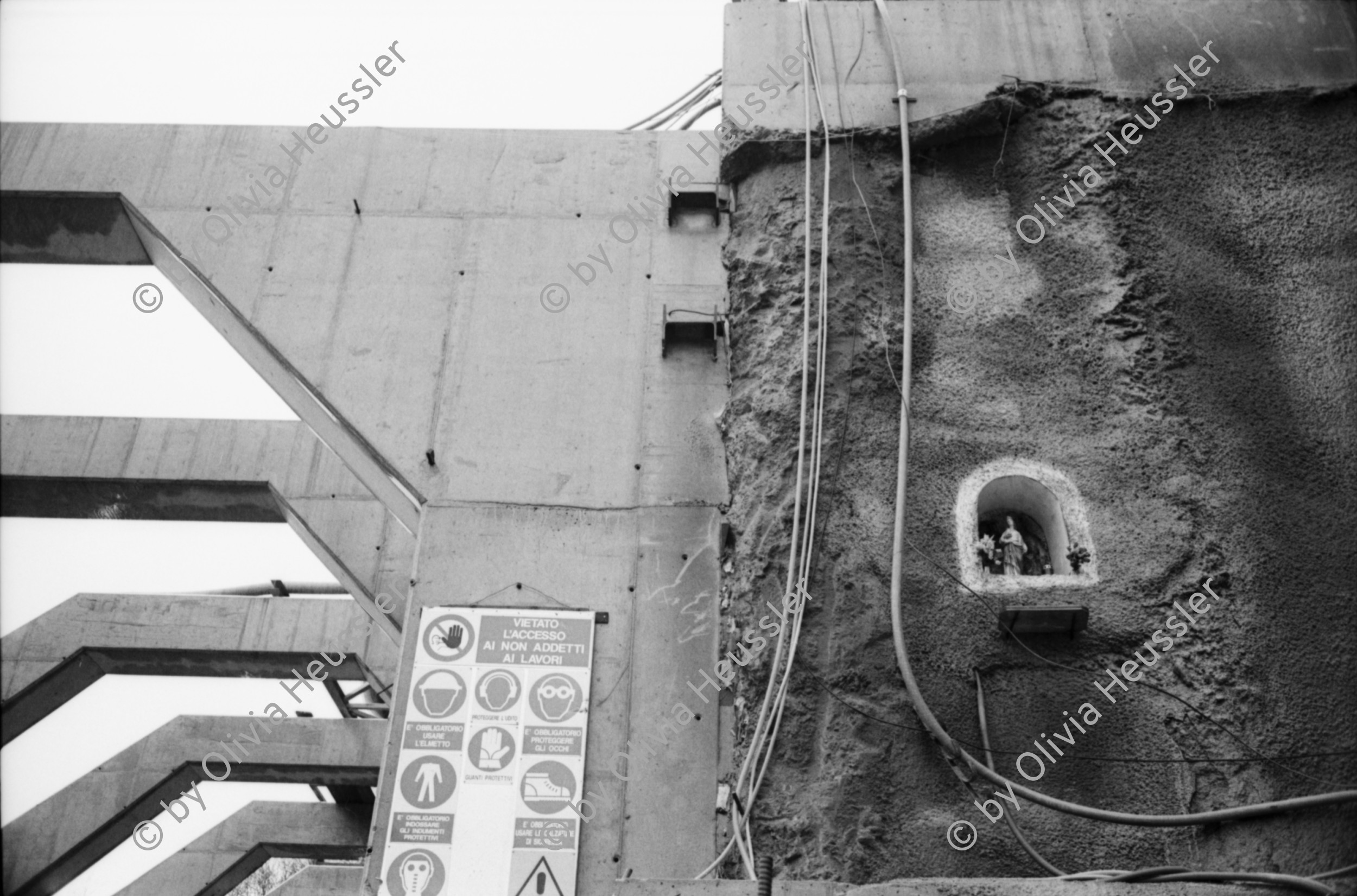 Image of sheet 20020790 photo 9: Neat Bahntunnel Gotthardbasistunnel Baustelle Suedportal
AlpTransit Gotthard AG  Südportal in Bodio 
Durchstich zur Oströhre Faido Gruppenbild Mineure zur Feier des ersten Durchbruchs im Basistunnel. 
...Wir sind zur Feier in den Gotthard-Basistunnel gekommen: den ersten Durchbruch im Jahrhundertbauwerk, nämlich von der Lockergesteinszone in die nördlich anschliessende Oströhre. Vor der Tunnelbrust steht erhöht wie auf einer Bühne ein gelber, von Scheinwerfern angestrahlter Bagger. Ende der Lockergesteinszone, die Tunnelbrust, auf der das auszubrechende Profil mit roten Punkten markiert ist, besteht aus solidem , monolithischem Leventinagranit. Die Mineure strömen in den Stollen, Lautsprecher werden montiert. ... Durch die Oeffnung sehen wir in die Oströhre hinüber...
Arbeiter der Firma Herrenknecht an der TBM
aus: Gotthard, das Hindernis verbindet. Kanton Tessin, Ticino, Schweiz Svizzera, Switzerland 2002