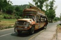 Image of sheet 20030030 photo 30: Pakistan 'Piyo aur jiyo!' Drinke und Lebe! Néstle wirbt an einer Hauswand für ihr Trinkwasser 
Gasbetriebene Fahrzeuge Autos mit Gas Tankstelle Love is life steht an einer Mauer dahinter Gras Marihuana pflanzen wilde Verkehrskreisel mit Atombombe