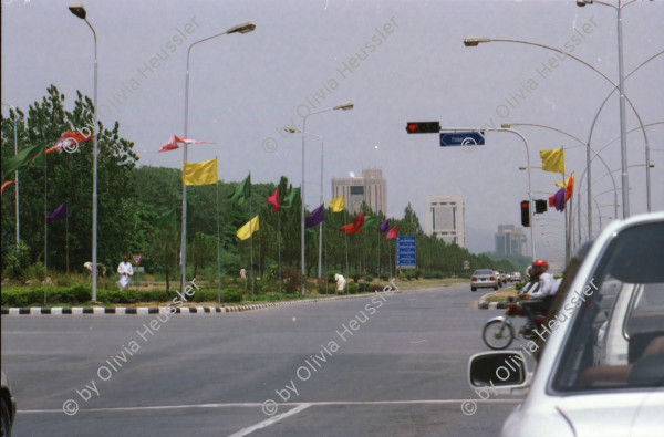 Image of sheet 20030030 photo 9: Pakistan 'Piyo aur jiyo!' Drinke und Lebe! Néstle wirbt an einer Hauswand für ihr Trinkwasser 
Gasbetriebene Fahrzeuge Autos mit Gas Tankstelle Love is life steht an einer Mauer dahinter Gras Marihuana pflanzen wilde Verkehrskreisel mit Atombombe