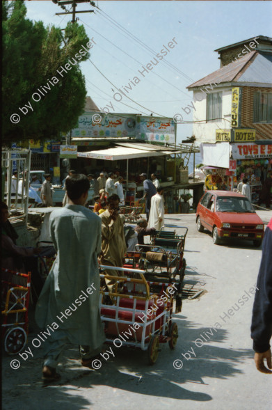 Image of sheet 20030050 photo 5: Murree ist eine Kleinstadt in der Provinz Punjab in Nord-Pakistan
Kinder mit farbigen Ballonen Hotel alter Mann und Schimmel weisses Pferd steht am Eingang Blecksoldaten zum abknallen mit dem Luftgewehr Spiel alte Bäume