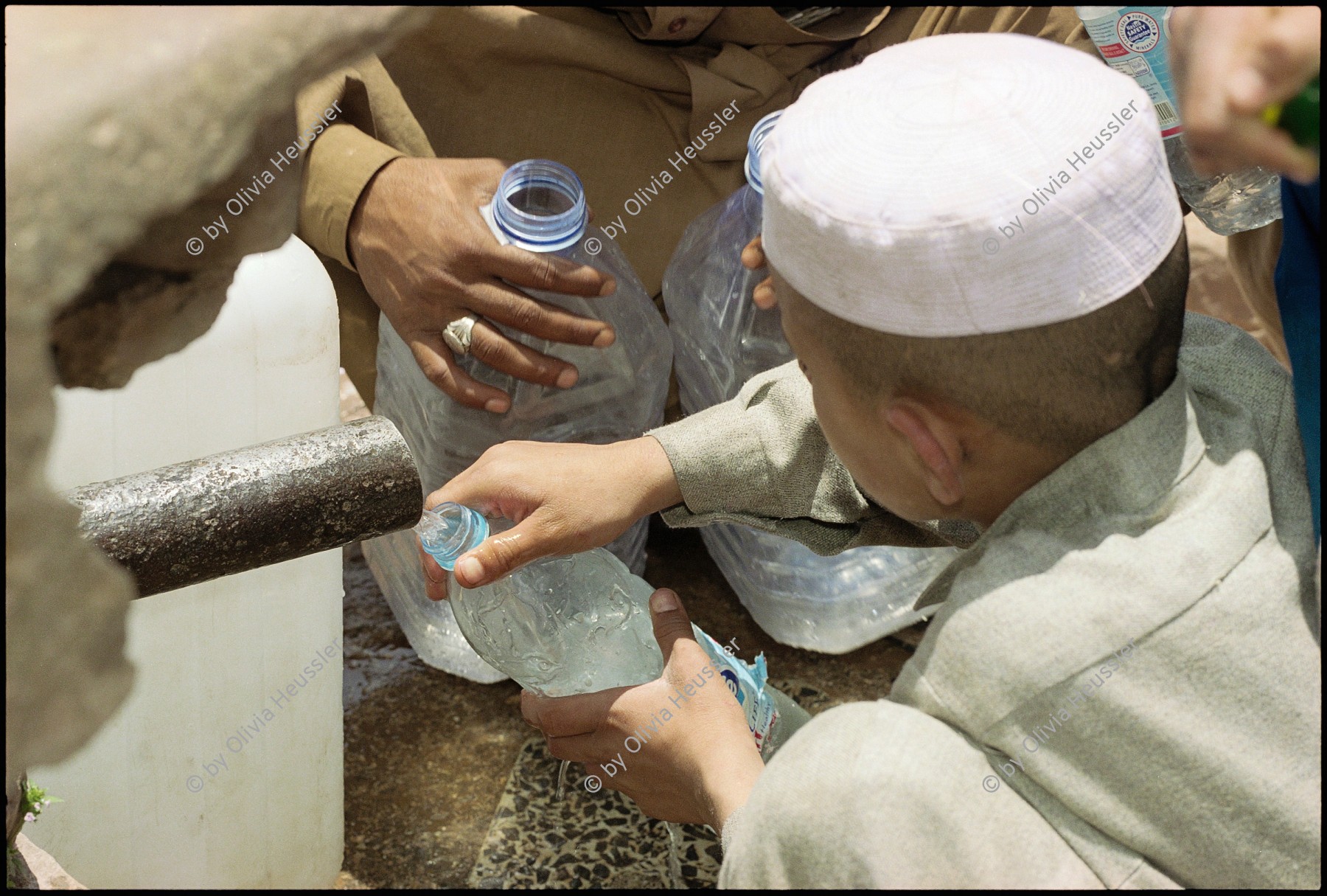 Image of sheet 20030070 photo 0: Männer beim Abfüllen von Trinkwasser in alte Nestlé Petflaschen an einem Brunnen. Pet Flasche Wasser water trinken Pakistan