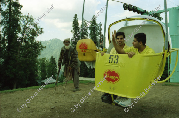 Image of sheet 20030070 photo 30: Car Transport auf der Strasse von der Hauptstadt Islamabad nach Murree M. ist eine Kleinstadt in der Provinz Punjab in Nord-Pakistan Ajubia Park
Ayubia is small town in the Khyber-Pakhtunkhwa province of Pakistan. It is located near the Murree hills and Galyat and is home to Ayubia National Park. It is a very famous tourist destination and includes one of the oldest chair lifts of the area.
Leute Männer und Frauen beim Wasser holen mit Flaschen. Frauen Bäume im Galyat tal
(eine der ältesten) Gondelbahn auch für Familien im National Park. Farige Fahnen und ein Bube mit Blumen Haarschmuck