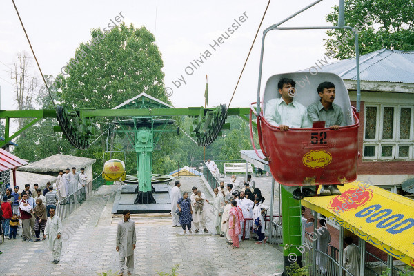 Image of sheet 20030080 photo 5: Ayubia is a small town in the Khyber-Pakhtunkhwa province of Pakistan. It is located near the Murree hills and Galyat and is home to Ayubia National Park. It is a very famous tourist destination and includes one of the oldest chair lifts of the area. 
Familien warten bei der Talstation auf eine freie Sesselbahn. Zwei Männer sitzen und fahren in einer Gondelbahn Station Sesselbahn
23/05/2003 
Tourismus Touristen