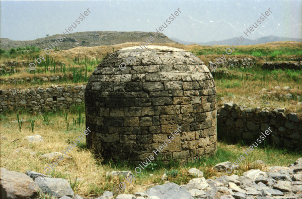 Image of sheet 20030120 photo 15: Sirkap (Urdu: سر کپ) is the name of an archaeological site on the bank opposite to the city of Taxila, Punjab, Pakistan. The city of Sirkap was built by the Greco-Bactrian king Demetrius after he invaded ancient Pakistan around 180 BC. Demetrius founded in the northern and northwestern Indian subcontinent (modern day Pakistan) an Indo-Greek kingdom that was to last until around 10 BC. Sirkap is also said to have been rebuilt by king Menander I. Wasserbrunnen, Mauern Mann im Schatten restauriert In den Stupas Nr. 14a wurden die Mönche eingeäschert. Männer baden schwimmen Khanpurkanal in einem Wasserkanal der Wasser nach Islamabad bringt. Eine Familie recycles sammelt Petflaschen und Abfall.