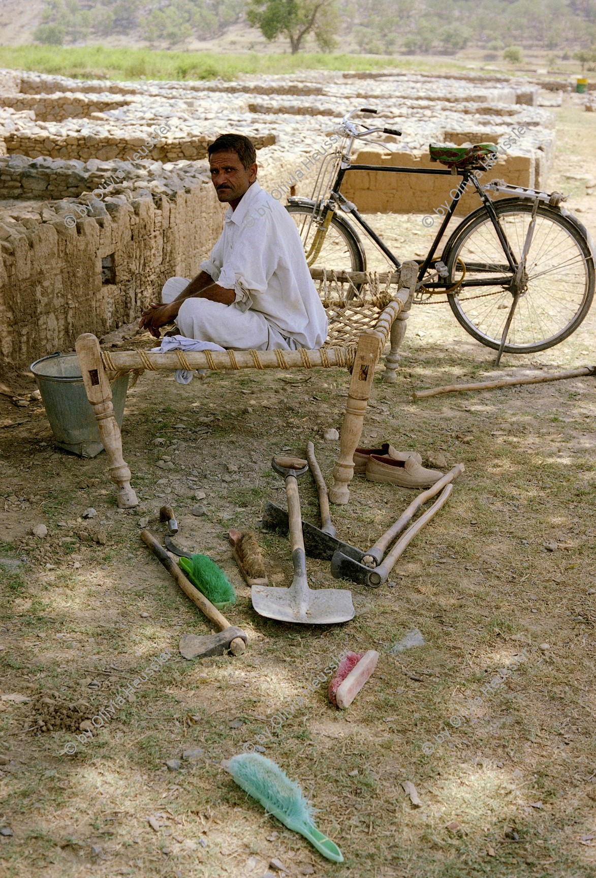 Image of sheet 20030120 photo 19: Mann sitzt im Schatten eines Baumes. Er macht Ausgrabungen. Im Vordergrund liegen seine Werkzeuge. Arbeit Ausgrabungen Archeology Archäologie
Pakistan Taxila Sirkap: Restaurierungsarbeiten einer Befestigungsmauer der alten Griechen aus dem 2 Jahrhundert vor Christus. 23/05/2003 OBJE_ Pakistan Punjab Taxila Sirkap. Man is working in the orderly walled city of sirkap builded by the Bactrian Greeks 2nd century BC.