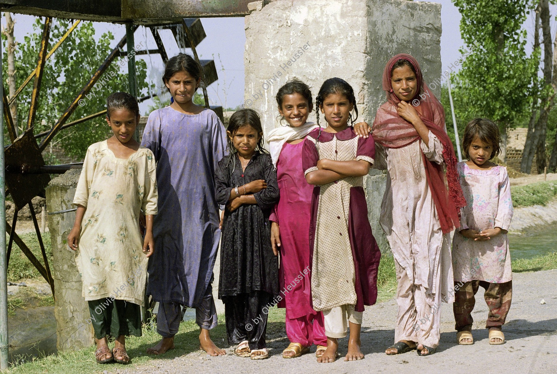 Image of sheet 20030130 photo 33: Kinder und Mädchen Gruppenbild stehen vor einem Wasserrad an einem Kanal.

Pakistan, Islamabad: Junge Mädchen posieren vor einer Wassermühle. 25/05/2003 OBJE_ Pakistan Punjab Taxila. A Group of girls stands in front of a watermill.