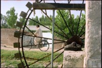 Image of sheet 20030140 photo 13: Mann fährt auf einem Fahrrad an einem Wasserrad vorbei. Pakistan 
water mill Man on Bike near Taxila