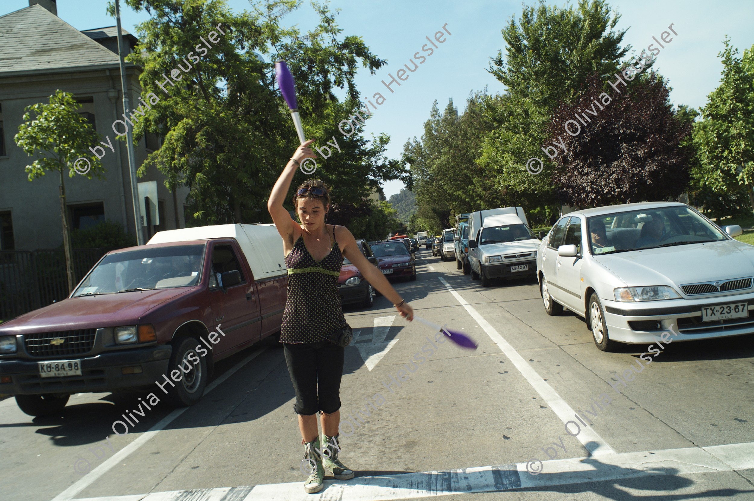Image of sheet 20051129 photo 509: Carolina works as a street artist at the corner of Avenida Francisco Bilbao and Calle Ramon Carnicer in Santiago de Chile 
 Latinamerica Lateinamerika South 
youth work women woman Streetworker Jonglieren Zirkus Zircus Cars trafic