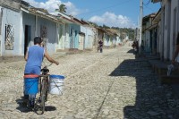 Image of sheet 20140215 photo 15: Ein Mann stösst in der Mittagssonne sein Fahrrad mit Wasser durch die Strasse in Trinidad Kuba 2014