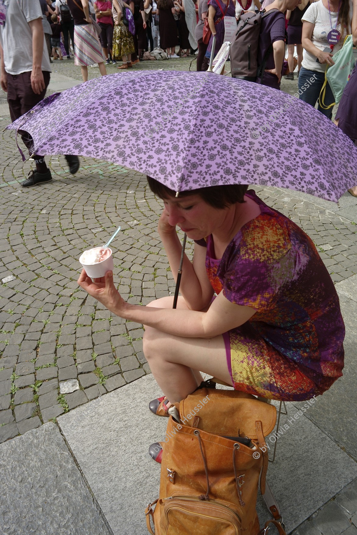 Image of sheet 20190614 photo 685: Eine elegante Dame geniesst sitzend unter einem Sonnenschirm am Frauenstreiktag ein kühlendes Eis.
die Frauen.
 Kreis 4 Aussersihl Helvetiaplatz
 Solidarity with Women strikers. Protest Strike Zürich 2019 Switzerland